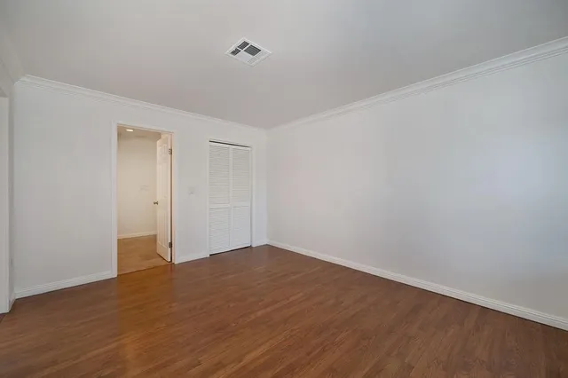 a view of an empty room with wooden floor and closet