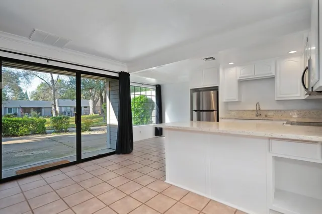 a large white kitchen with granite countertop a sink and a large window