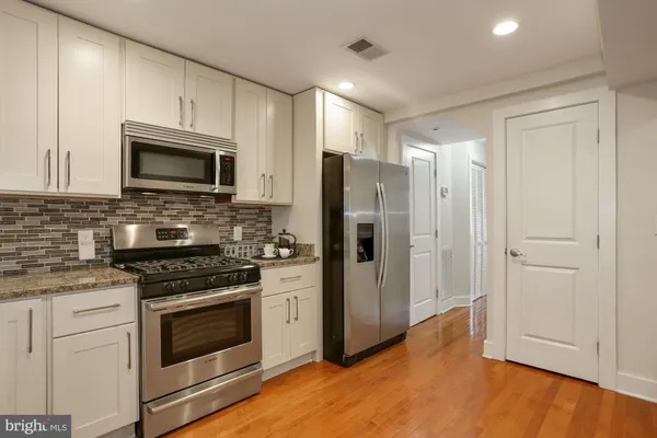 a kitchen with stainless steel appliances granite countertop a stove a refrigerator and a microwave