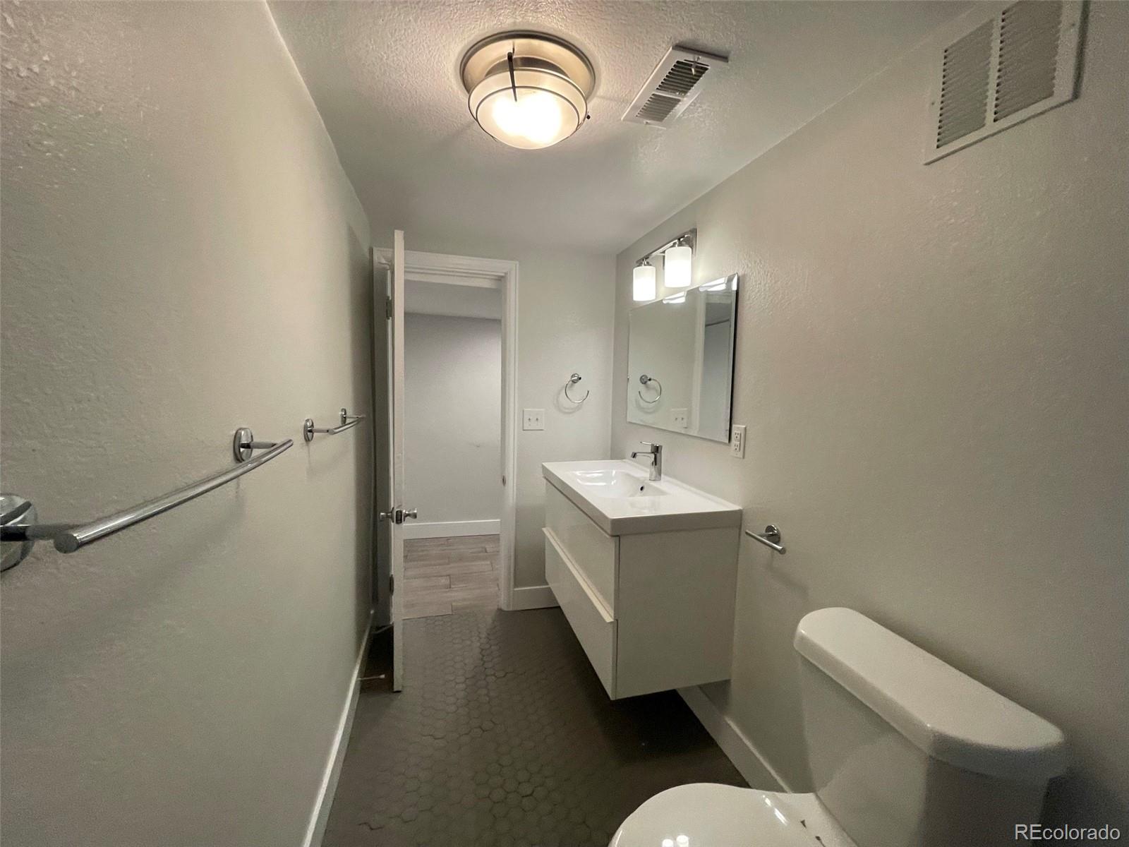 1691 Monroe Street Denver, CO 80206 - Photo 18 of 31 a spacious bathroom with a toilet sink and mirror