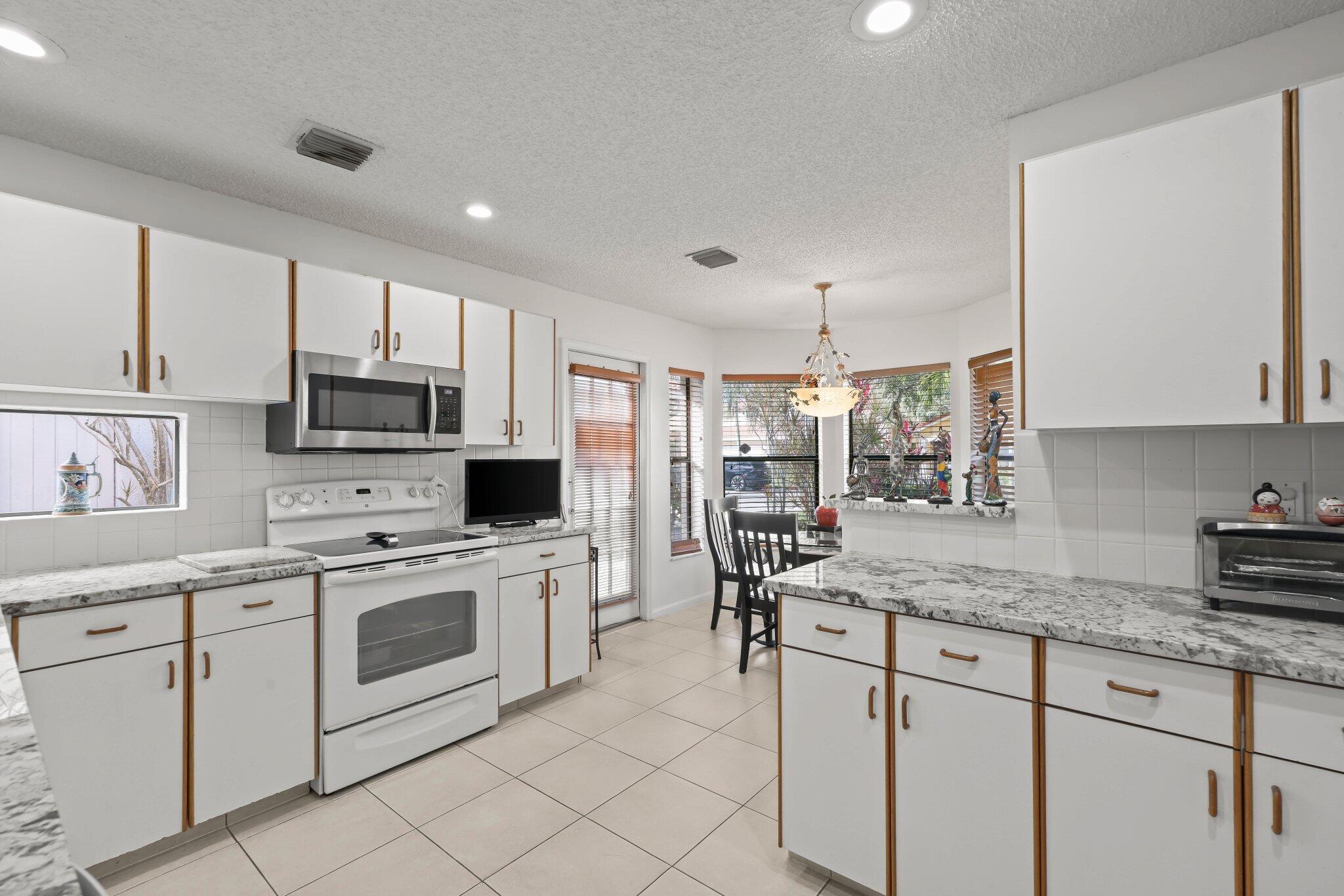 10678 Santa Laguna Drive Boca Raton, FL 33428 - Photo 14 of 40 a kitchen with granite countertop white cabinets white appliances and sink