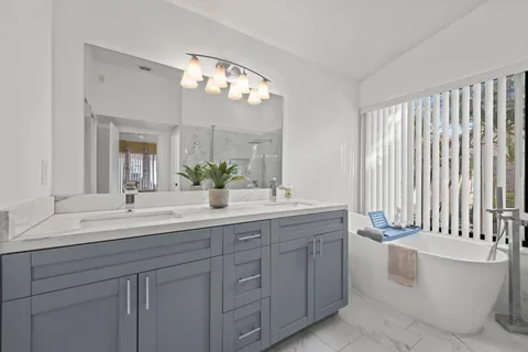 a spacious bathroom with a double vanity sink a large mirror a bathtub and