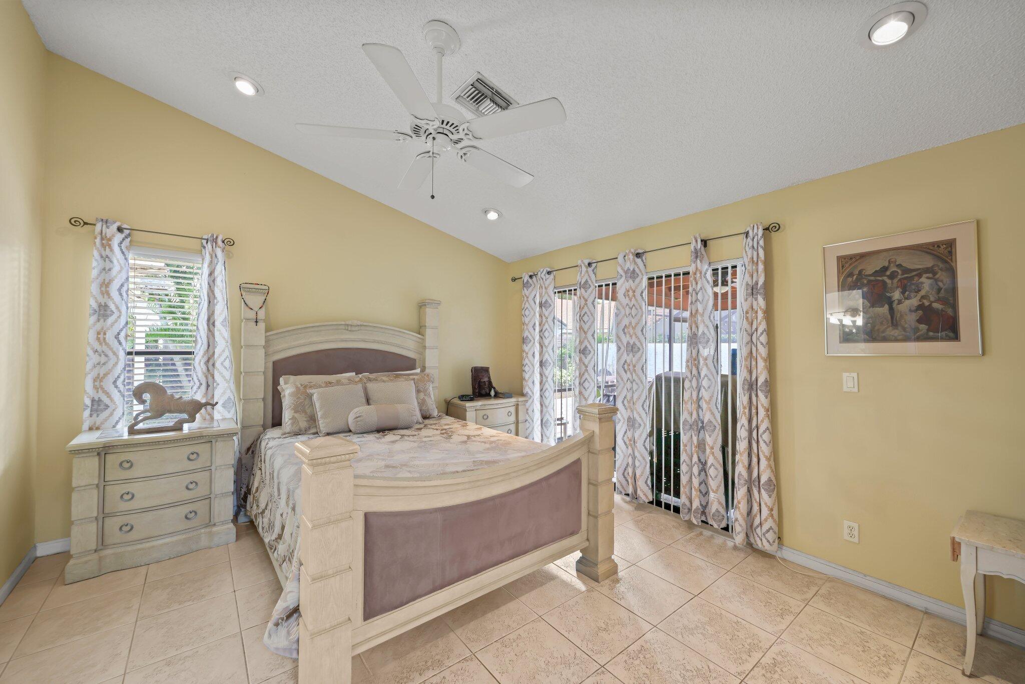 10678 Santa Laguna Drive Boca Raton, FL 33428 - Photo 5 of 40 a large bedroom with a bed and a chandelier