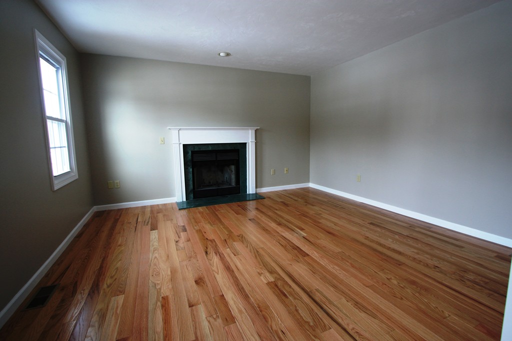 14 Cedar Hill Road Sutton, MA 01590 - Photo 10 of 16 an empty room with wooden floor a fireplace and windows