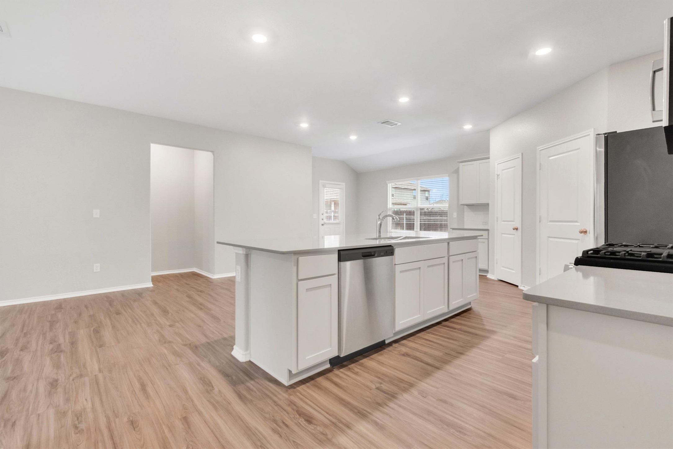 301 Blue Springs Pass Kyle, TX 78640 - Photo 13 of 20 Kitchen featuring white cabinets, stainless steel appliances, an island with sink, light wood-style flooring, and recessed lighting