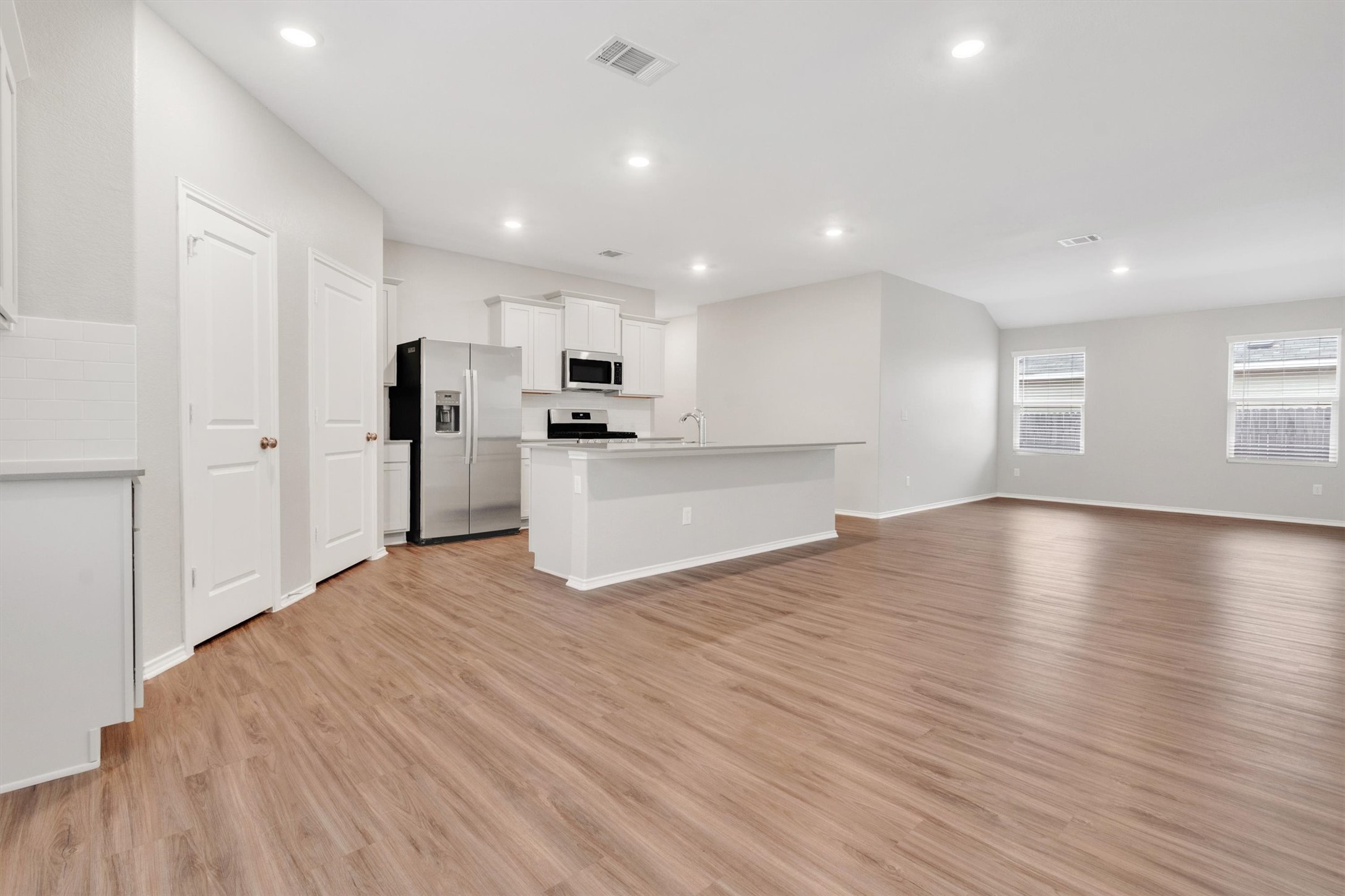 301 Blue Springs Pass Kyle, TX 78640 - Photo 20 of 20 Kitchen featuring stainless steel appliances, open floor plan, white cabinets, light wood-type flooring, and a kitchen island with sink
