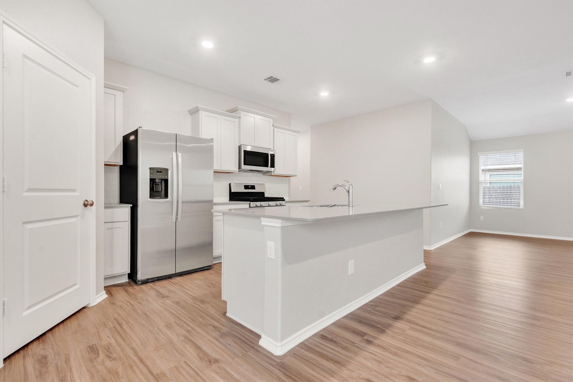 301 Blue Springs Pass Kyle, TX 78640 - Photo 17 of 20 Kitchen featuring stainless steel appliances, white cabinetry, light wood-style flooring, an island with sink, and recessed lighting