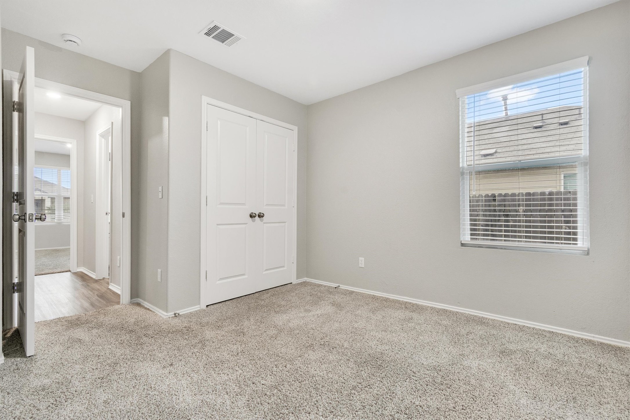 301 Blue Springs Pass Kyle, TX 78640 - Photo 5 of 20 Unfurnished bedroom with light carpet, a closet, and multiple windows
