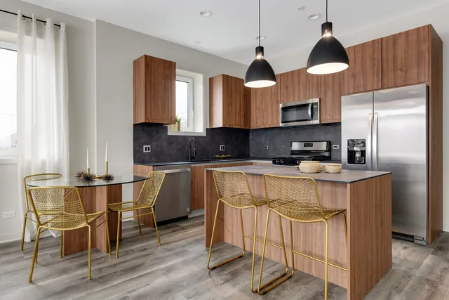 a kitchen with stainless steel appliances granite countertop a stove top oven a sink a dining table and chairs with wooden floor