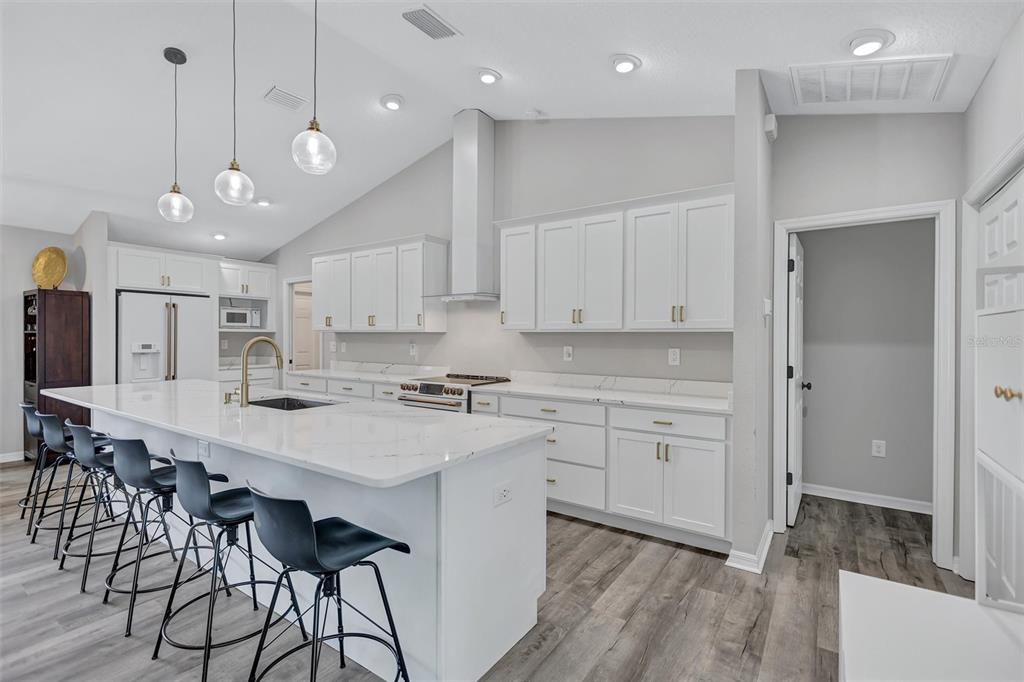 13362 Downy Woodpecker Road Weeki Wachee, FL 34614 - Photo 9 of 26 a kitchen with stainless steel appliances kitchen island granite countertop a stove a sink and a refrigerator