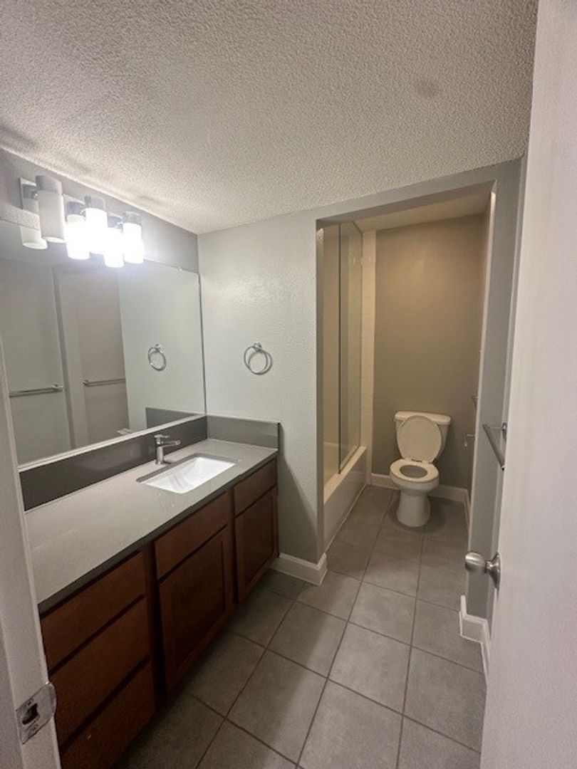 2520 Longview Street, Unit 405 Austin, TX 78705 - Photo 9 of 11 a spacious bathroom with a granite countertop sink a toilet and a mirror