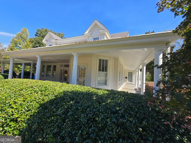 a view of a white house next to a yard