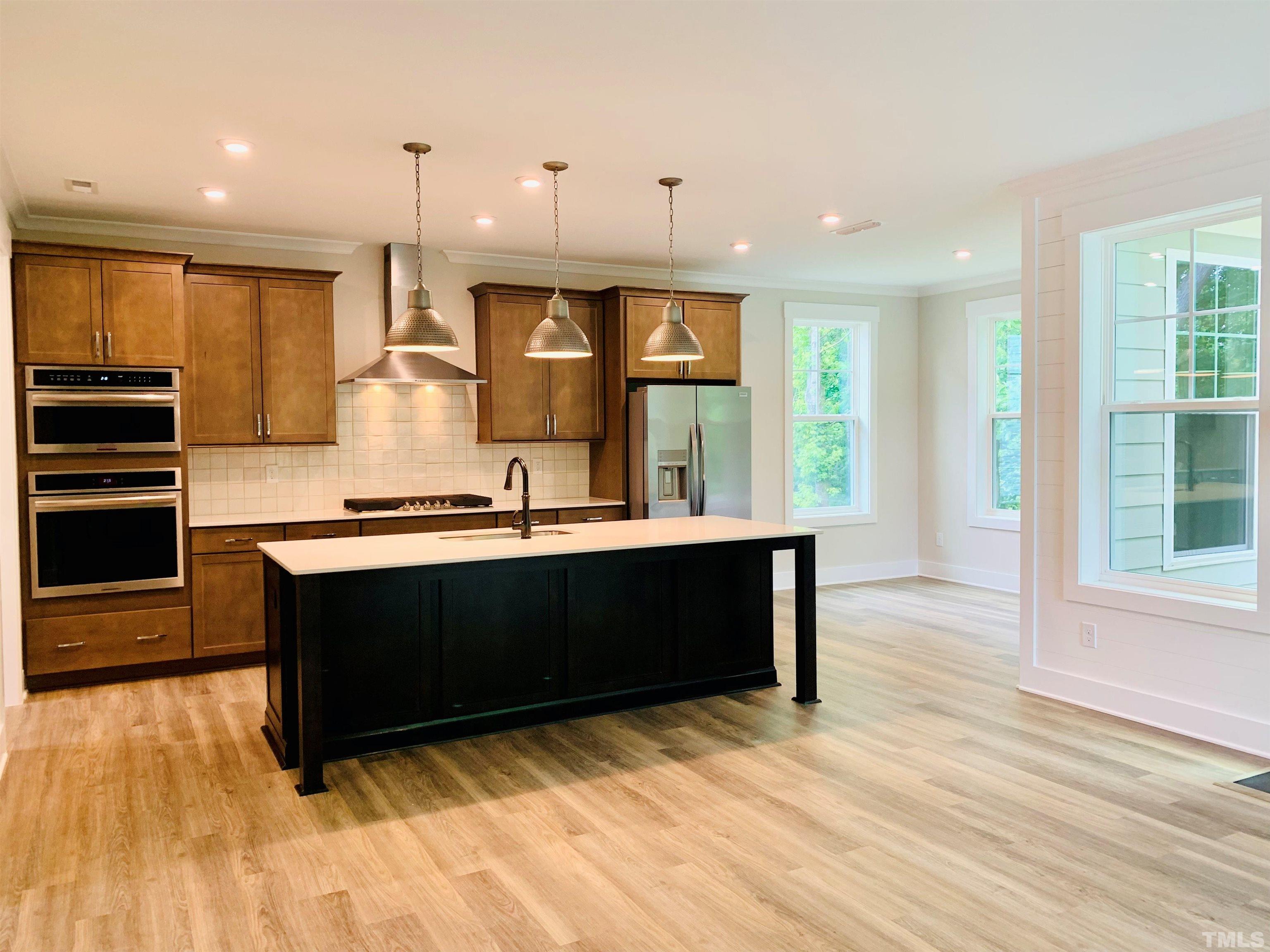 163 DUNLOE Loop Raleigh, NC 27603 - Photo 7 of 32 a kitchen with stainless steel appliances kitchen island granite countertop a stove a refrigerator and a wooden cabinets
