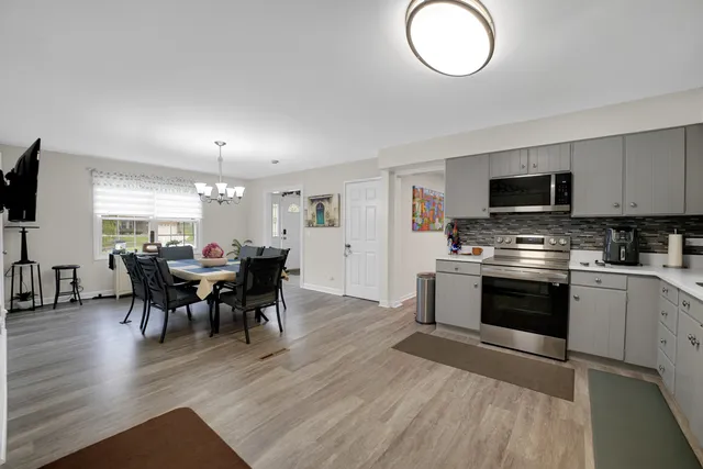 a kitchen with stainless steel appliances granite countertop a stove top oven a sink dishwasher a dining table and chairs with wooden floor