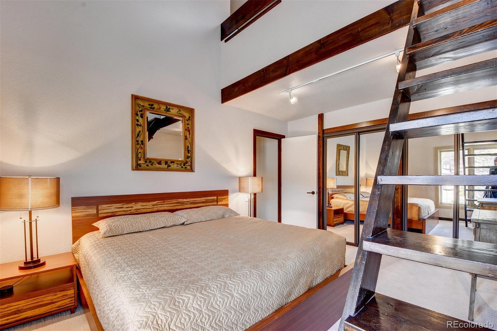 574 Spring Ranch Drive Golden, CO 80401 - Photo 24 of 40 a bedroom with a large bed and a lamp on table