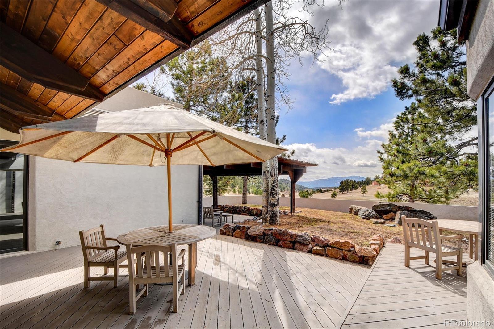 574 Spring Ranch Drive Golden, CO 80401 - Photo 29 of 40 a view of a patio with table and chairs under an umbrella with a barbeque