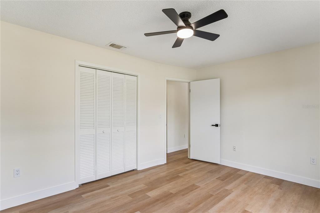 10194 Gamewell Street Spring Hill, FL 34608 - Photo 18 of 36 an empty room with wooden floor ceiling fan and windows