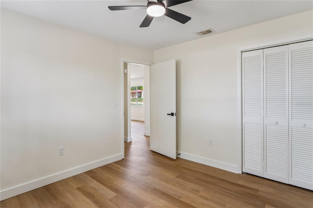 10194 Gamewell Street Spring Hill, FL 34608 - Photo 22 of 36 an empty room with wooden floor ceiling fan and windows