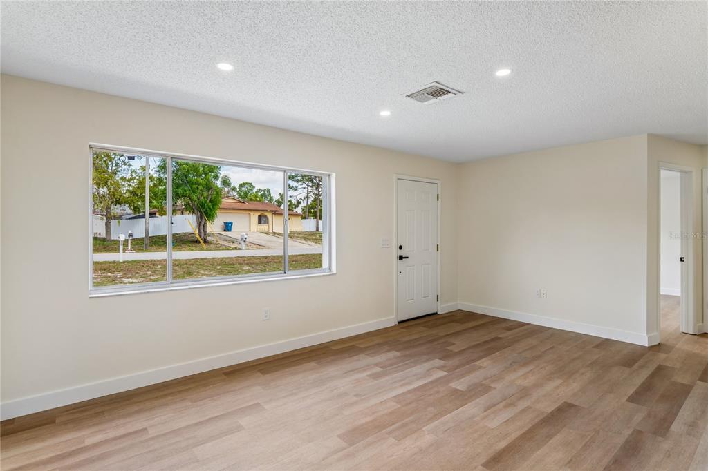 10194 Gamewell Street Spring Hill, FL 34608 - Photo 7 of 36 a view of an empty room with wooden floor and a window