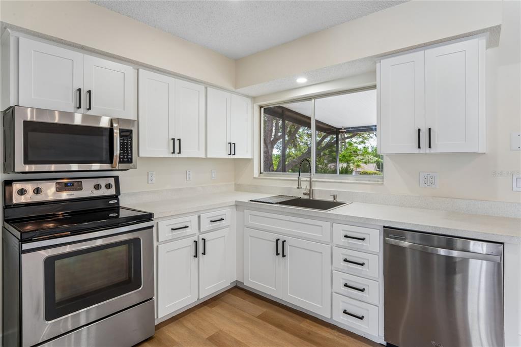 10194 Gamewell Street Spring Hill, FL 34608 - Photo 9 of 36 a kitchen with granite countertop a sink cabinets stainless steel appliances and a window