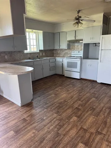 a kitchen with wooden floors and white cabinets