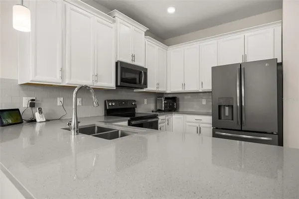 a kitchen with granite countertop a refrigerator and a stove top oven