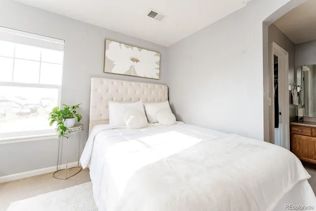 a large white bed in a bedroom next to a window