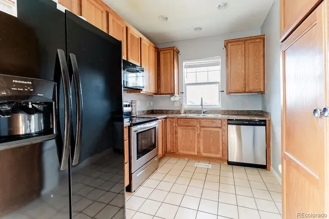a kitchen with granite countertop a refrigerator stove and sink