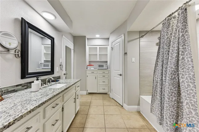 a bathroom with a granite countertop sink a mirror and a shower