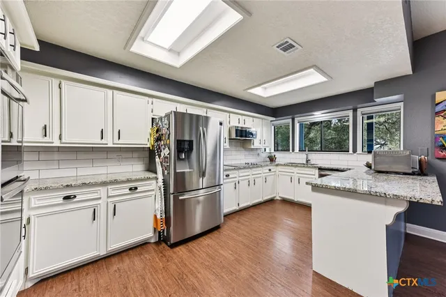 a kitchen with granite countertop a refrigerator and white cabinets