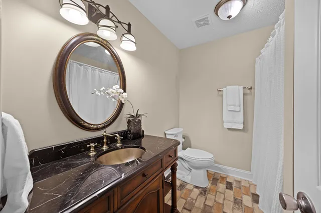 a bathroom with a granite countertop toilet a sink and a mirror