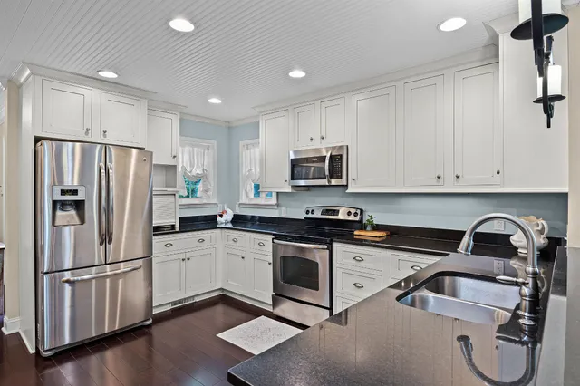a kitchen with a refrigerator sink and white cabinets