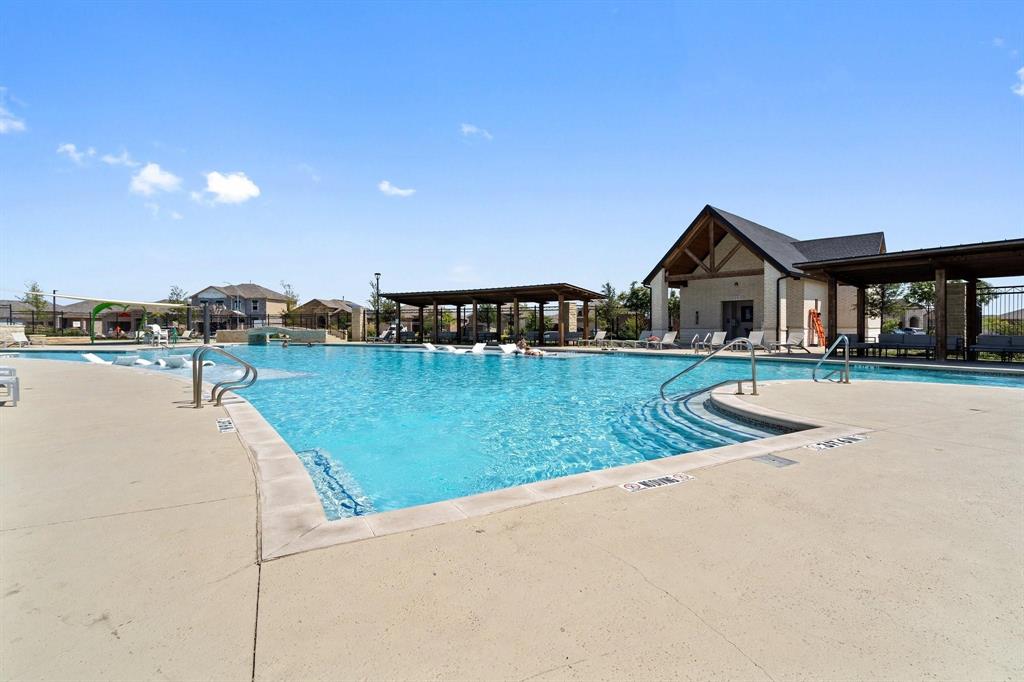 15932 Stableford Road Justin, TX 76247 - Photo 31 of 35 Expansive swimming pool with integrated steps, surrounded by a concrete deck, and shaded pergolas, featuring a central clubhouse structure