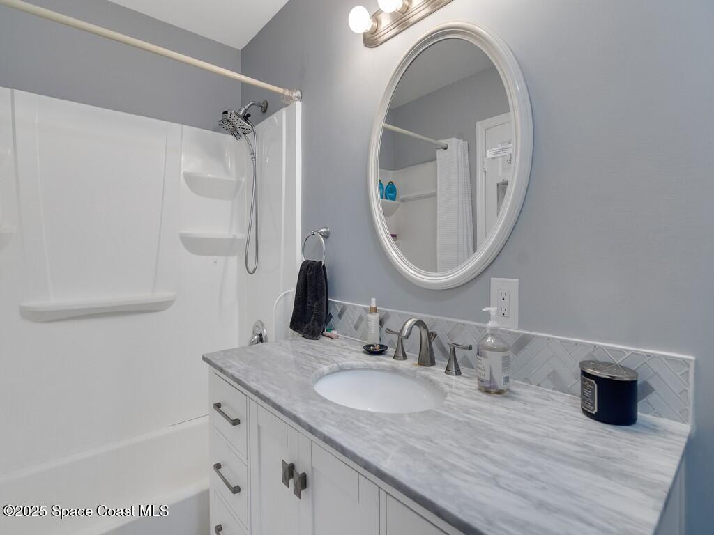 2020 Vero S Circle Southwest, Unit 4 Vero Beach, FL 32962 - Photo 13 of 33 a bathroom with a granite countertop sink a mirror and shower