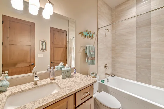 a bathroom with a granite countertop sink toilet mirror and a bathtub