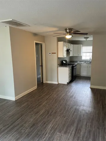 a kitchen with stainless steel appliances granite countertop a refrigerator a sink dishwasher a stove and white countertops with wooden floor