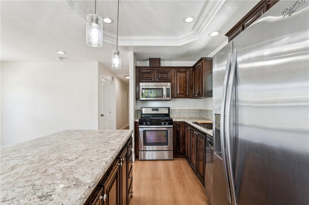 10550 Dunlap Crossing Road, Unit 141 Whittier, CA 90606 - Photo 10 of 38 a kitchen with stainless steel appliances granite countertop a refrigerator a stove and a sink with wooden floor