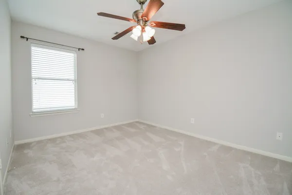 an empty room with a window and a fan