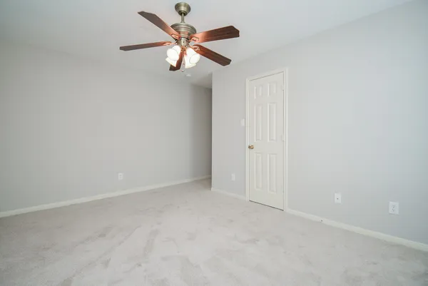 an empty room with a chandelier fan and windows