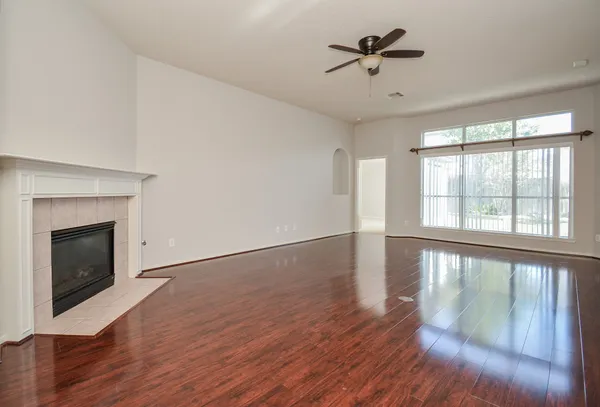 an empty room with wooden floor fan and windows