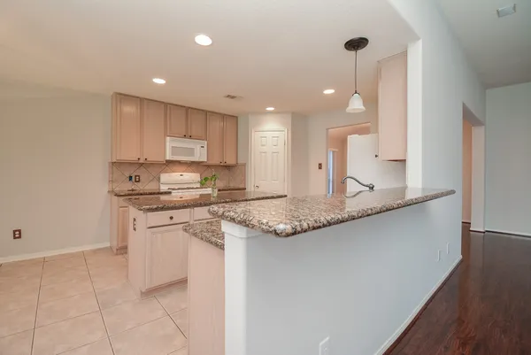 a kitchen with kitchen island granite countertop a sink a stove a refrigerator and white cabinets