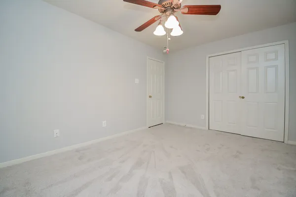 an empty room with a chandelier fan and glass door