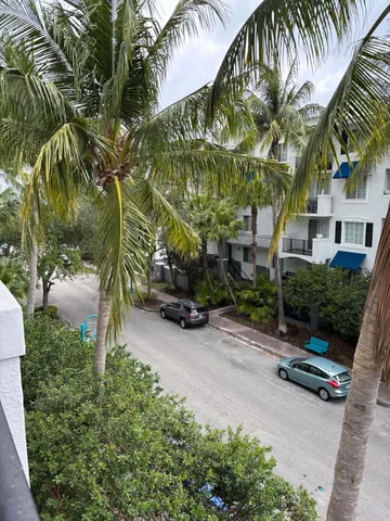 a backyard of a house with potted plants and palm trees