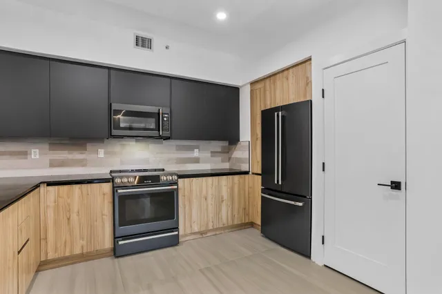 a kitchen with granite countertop a refrigerator and a stove top oven