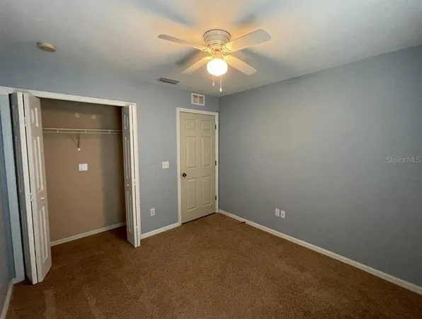 an empty room with closet and a chandelier fan