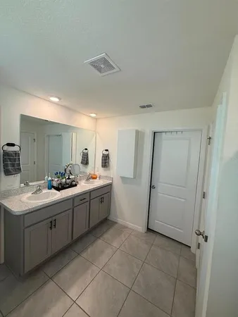 a large bathroom with a double vanity sink a toilet and a mirror