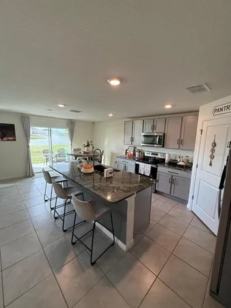a kitchen with stainless steel appliances granite countertop a table chairs sink and cabinets