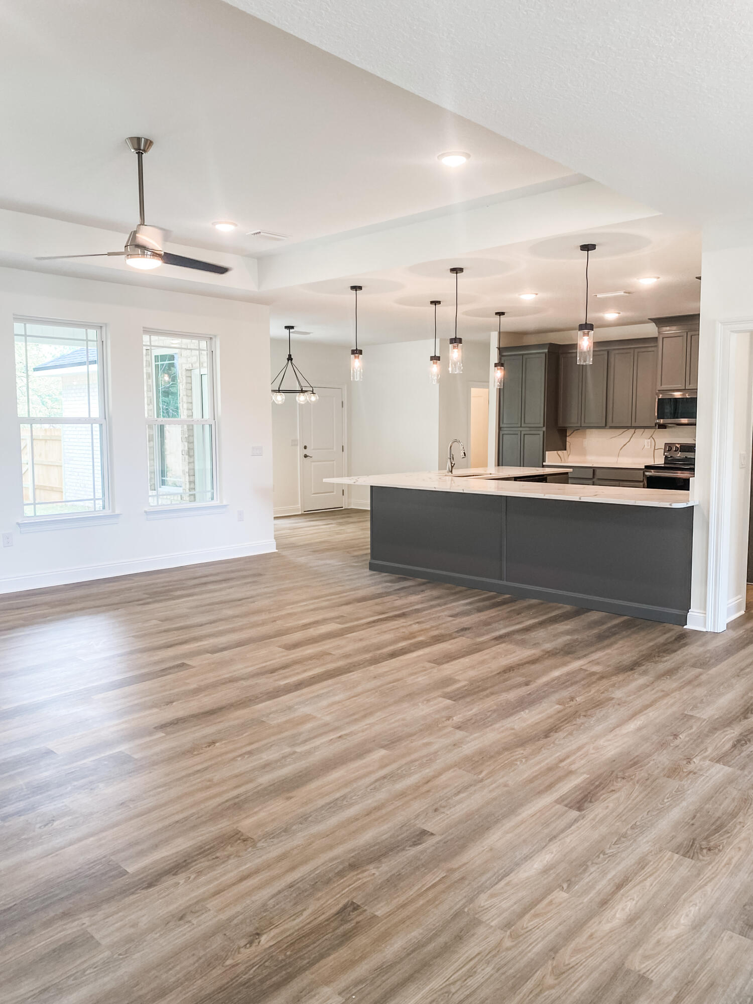 5464 Jenee Court Crestview, FL 32539 - Photo 4 of 10 an empty room with wooden floor and kitchen view