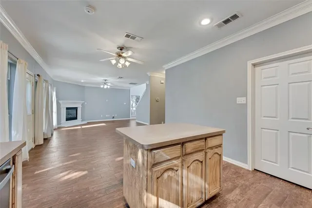 a hall with kitchen island hardwood floor and a ceiling fan