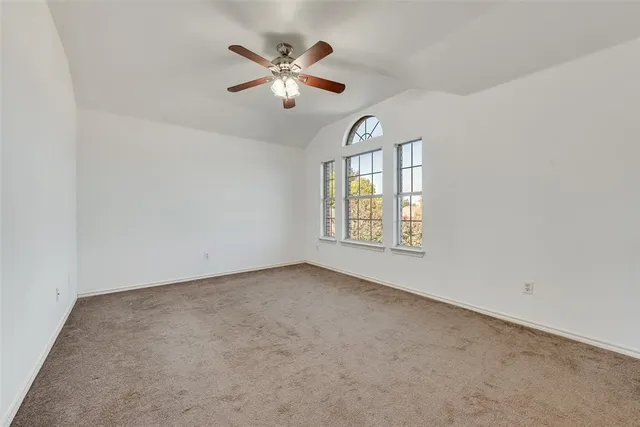 an empty room with windows and chandelier fan